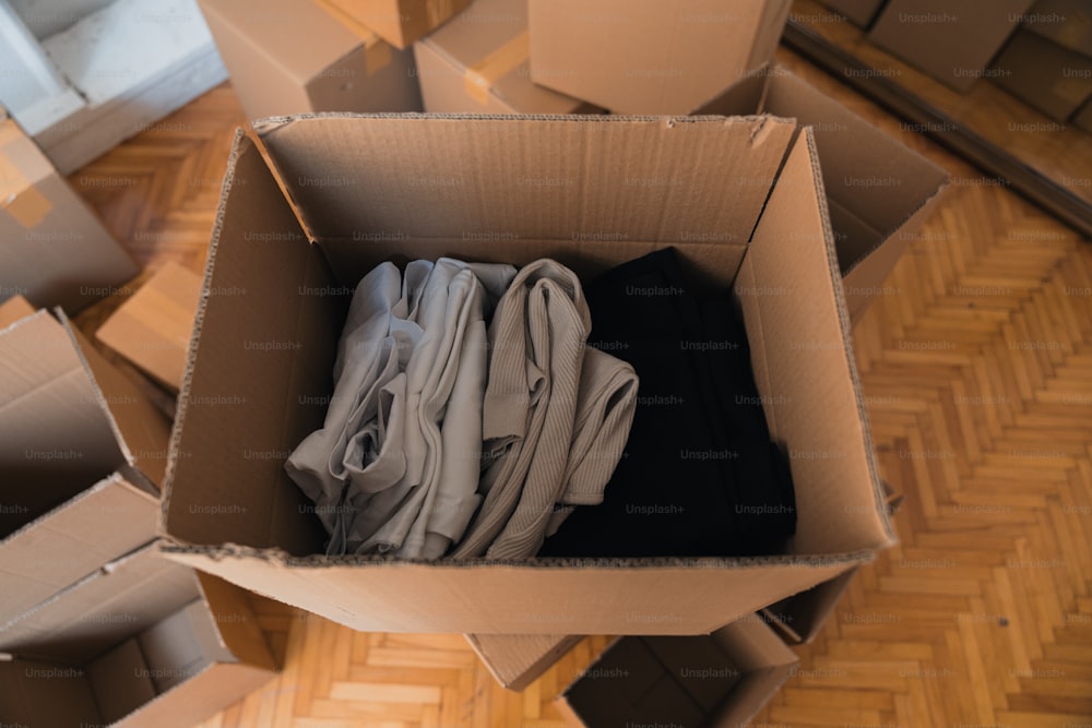 une boîte en carton remplie de vêtements sur un plancher en bois