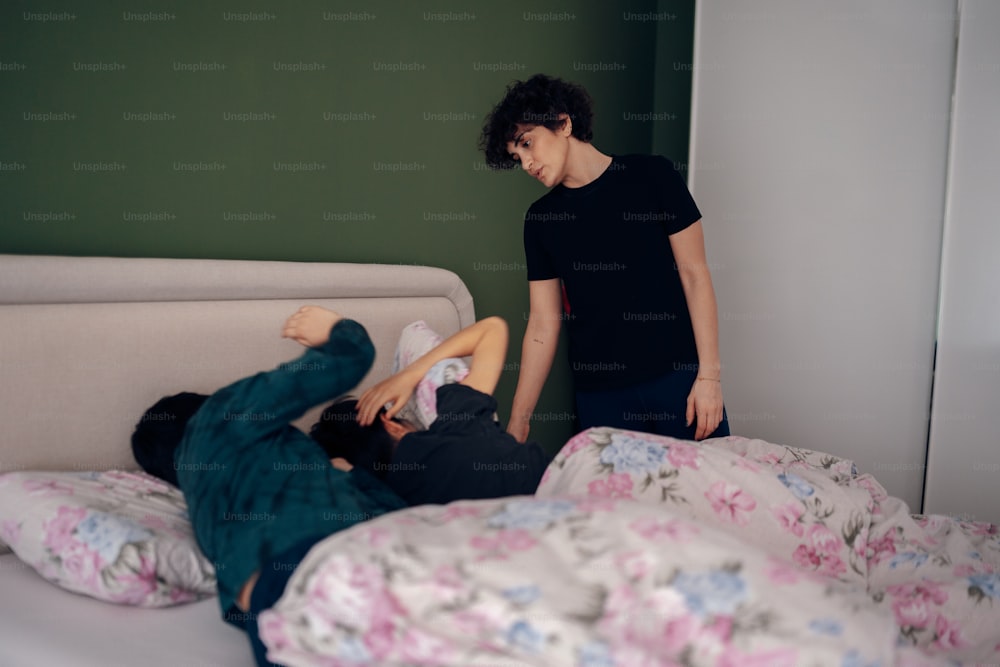 a woman standing next to a man laying on top of a bed