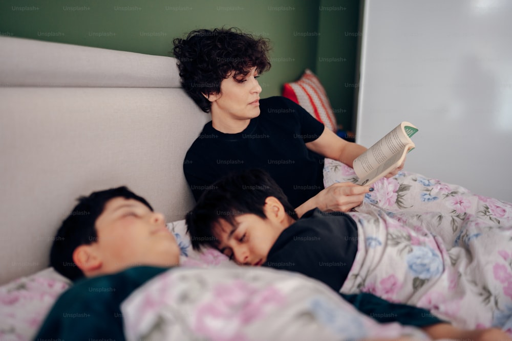 a woman reading a book to a boy laying in bed