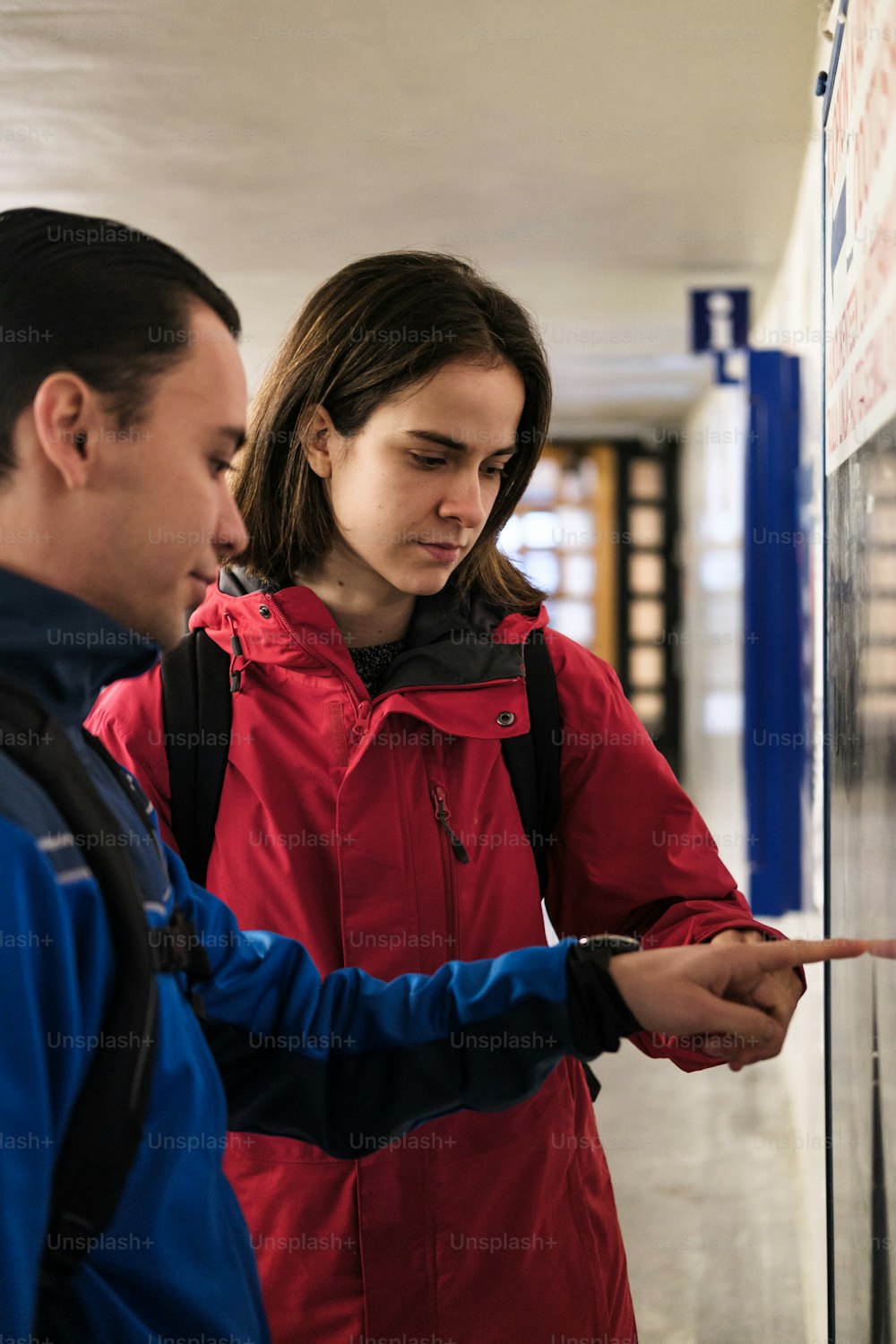 a man and a woman looking at something on a wall