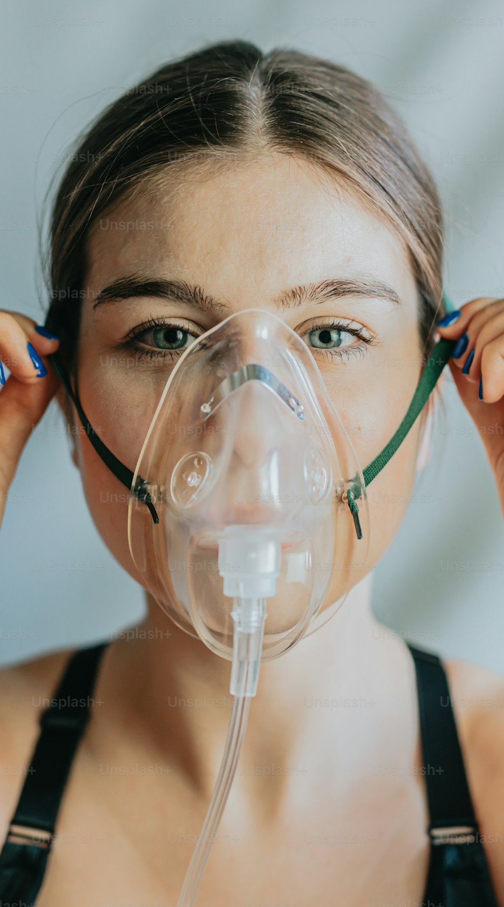 Eine Frau, die eine Sauerstoffmaske mit einem Atemschlauch im Gesicht trägt