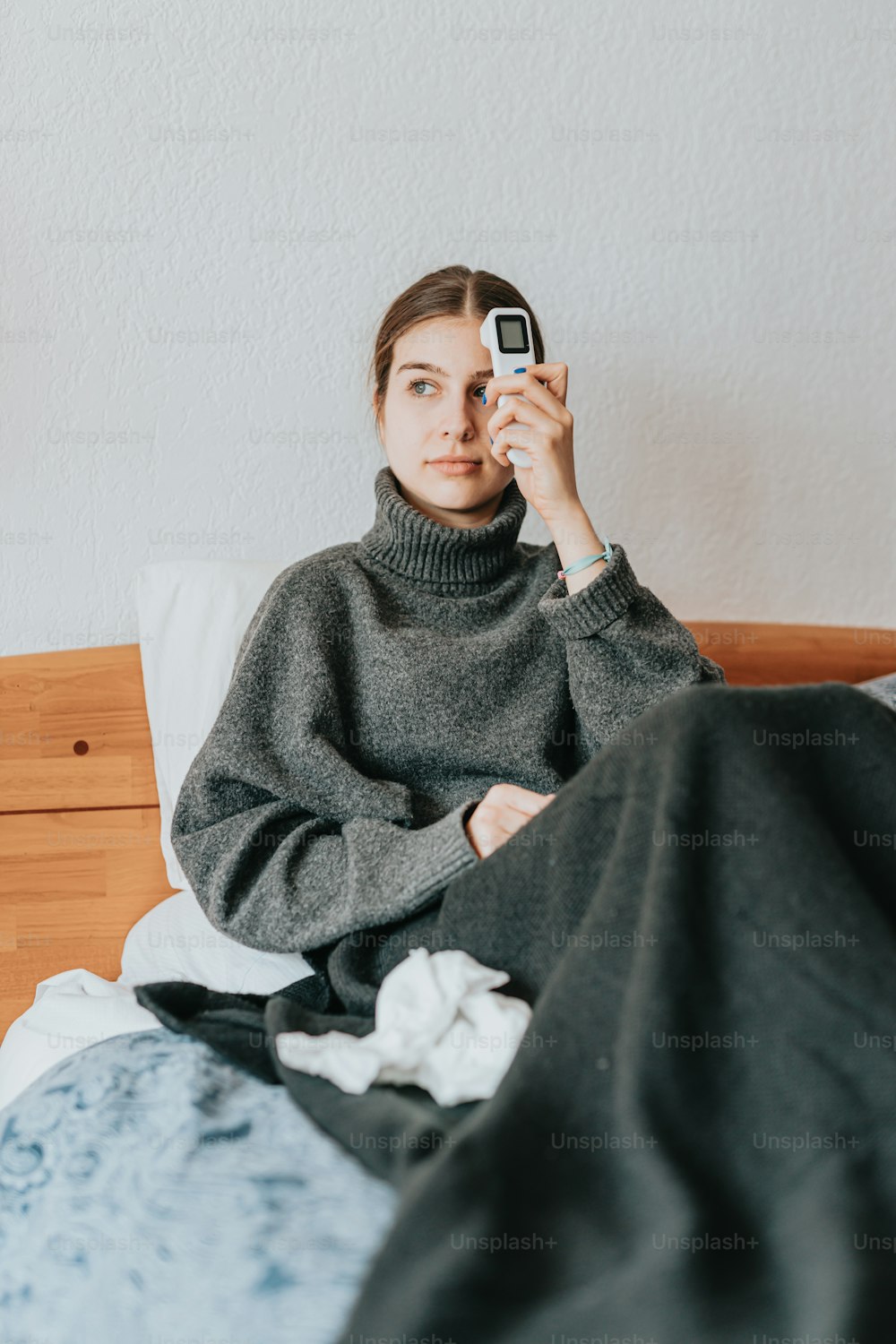 a woman sitting on a bed holding a cell phone