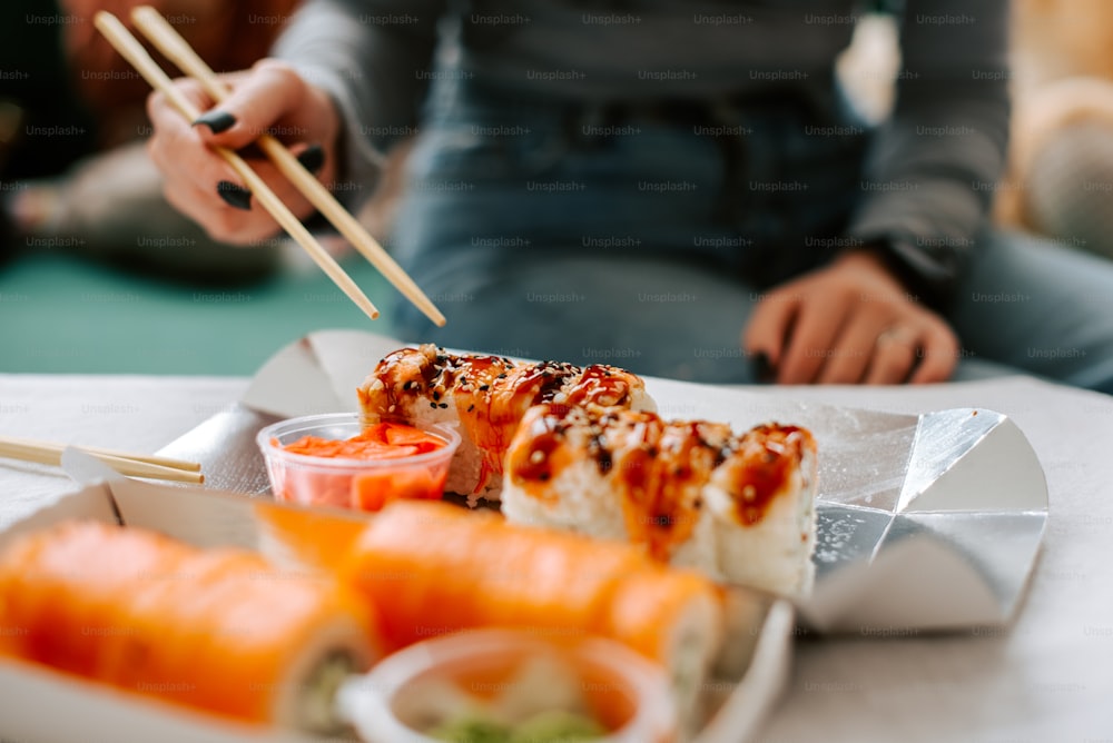 um prato de sushi e pauzinhos em uma mesa
