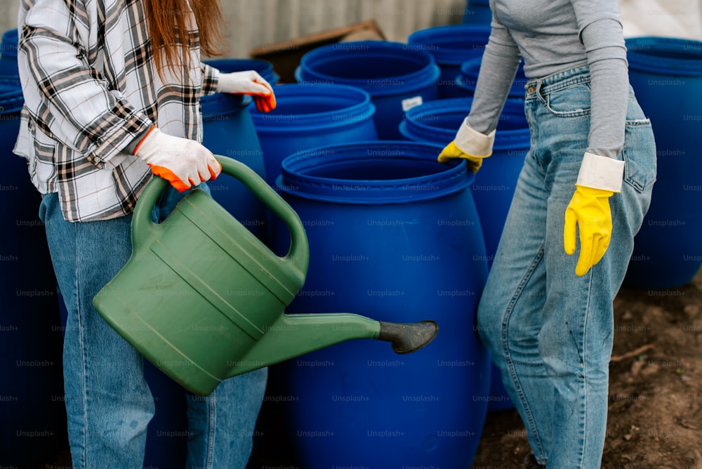 a woman holding a green watering can next to another woman