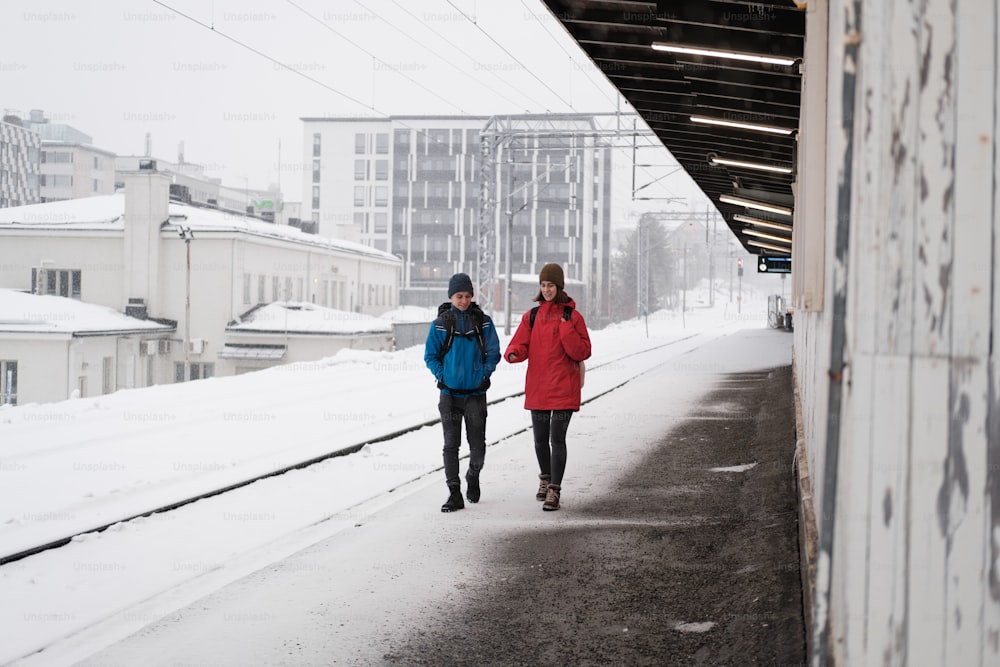 um casal de pessoas andando por uma estrada coberta de neve