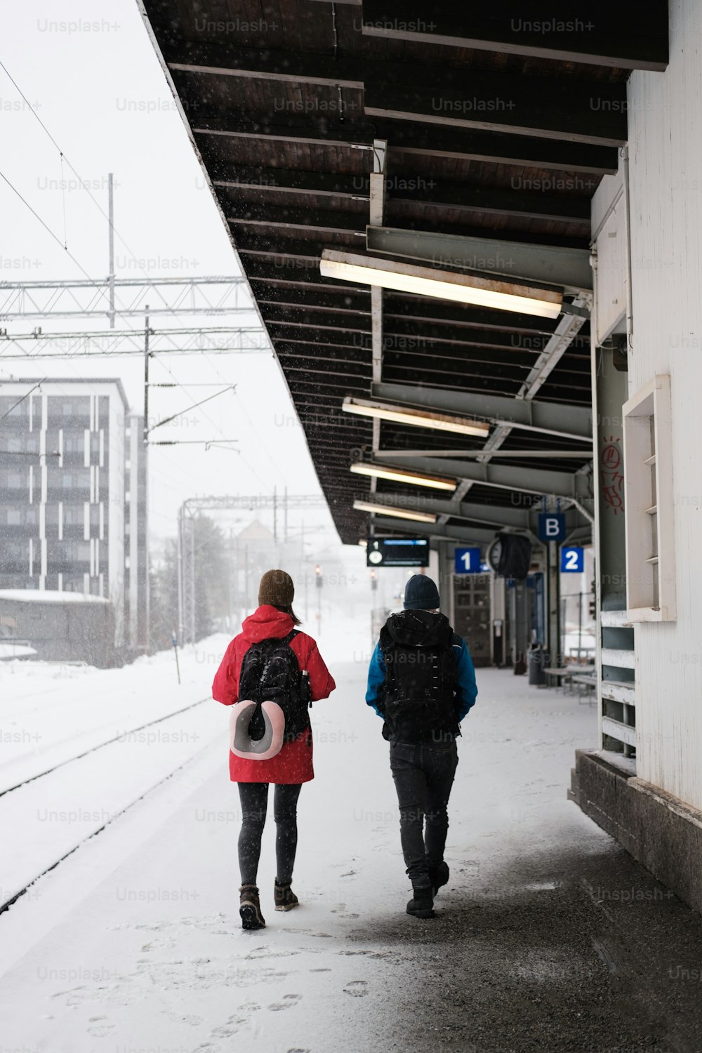 Ein paar Leute gehen einen schneebedeckten Bürgersteig entlang