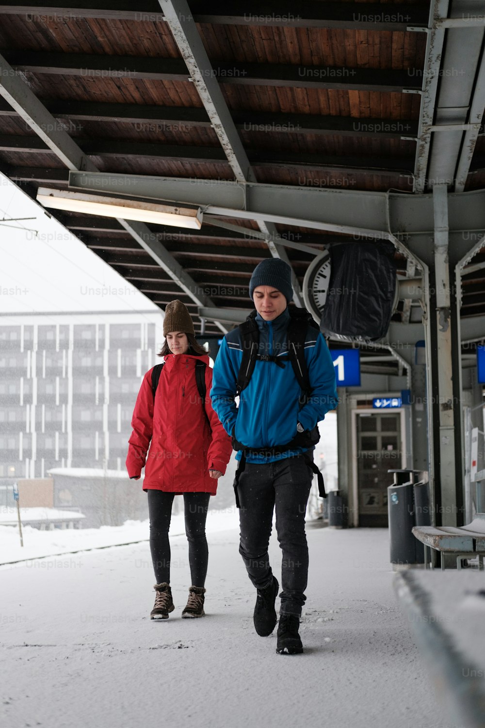 Un par de personas caminando por una acera cubierta de nieve