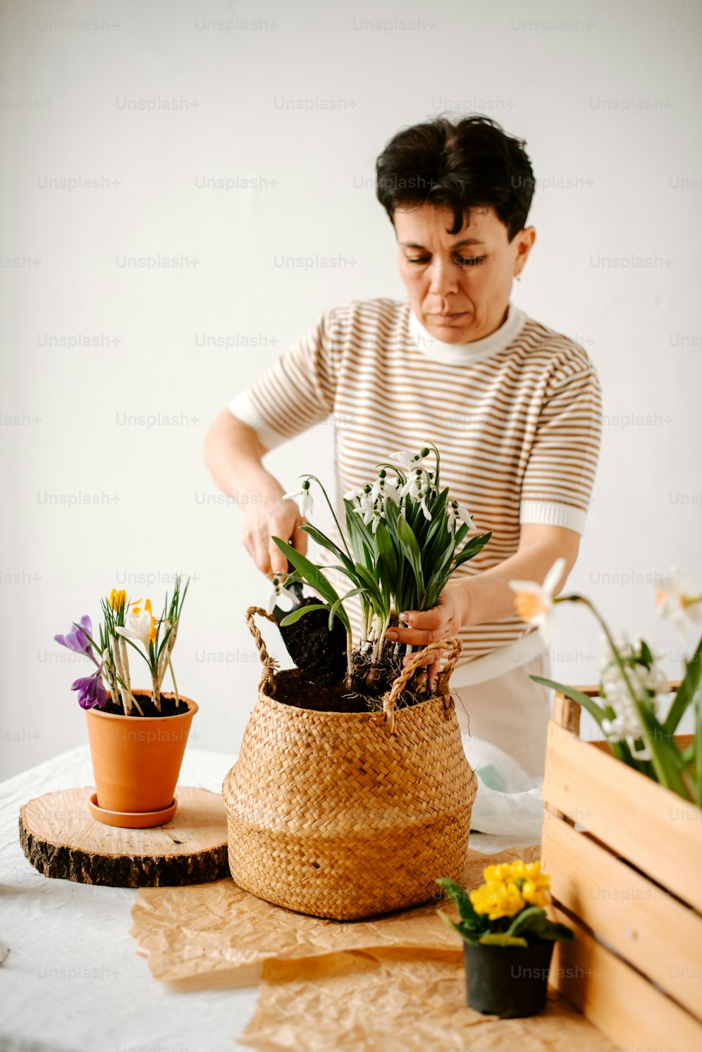 a woman arranging flowers in a basket on a table