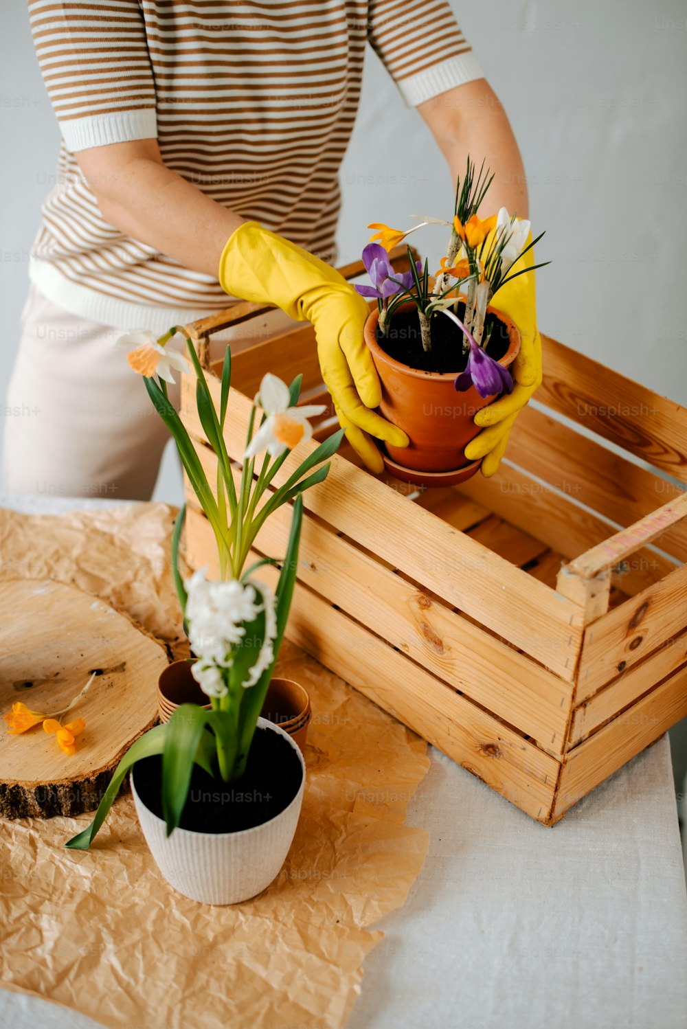 a woman in yellow gloves is arranging flowers