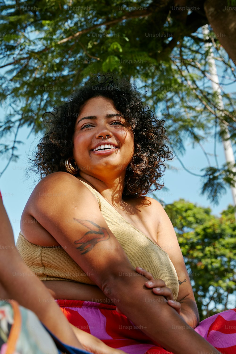 Una mujer en bikini sentada bajo un árbol