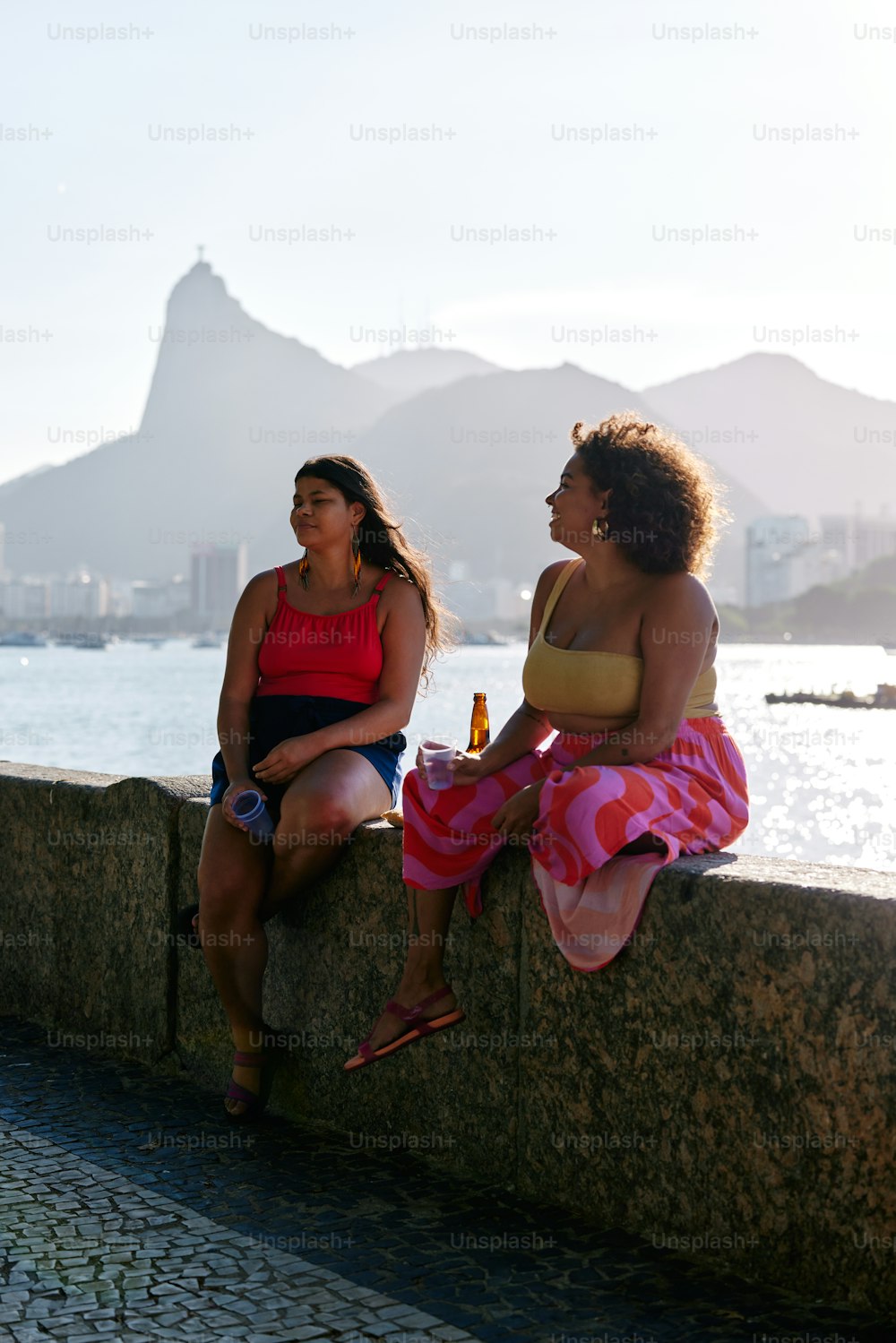 a couple of women sitting on top of a stone wall