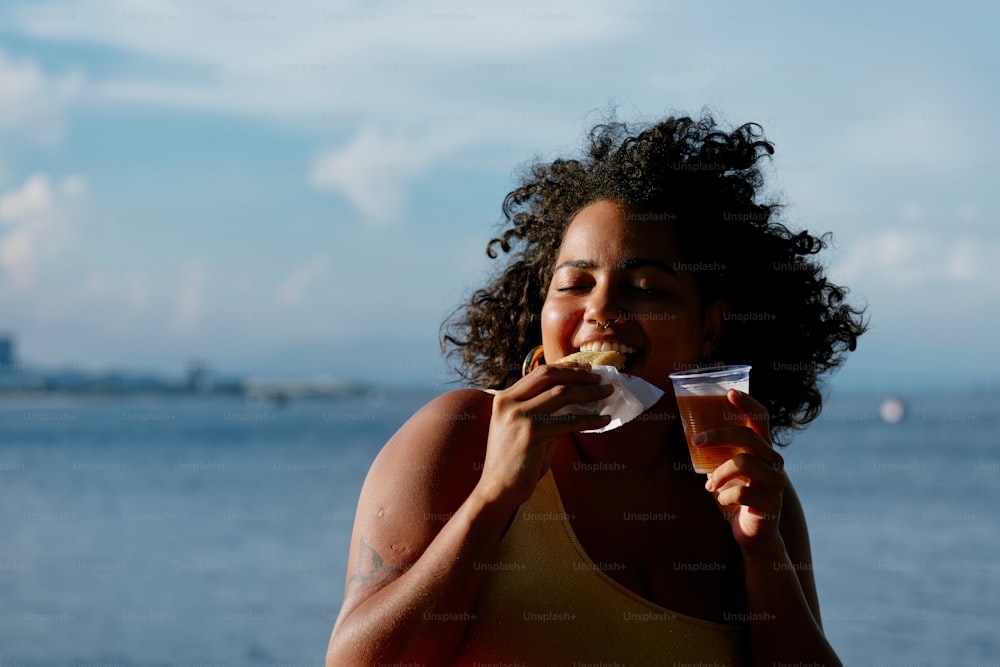 a woman eating a donut by the ocean