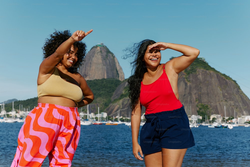 two women standing next to each other on a beach