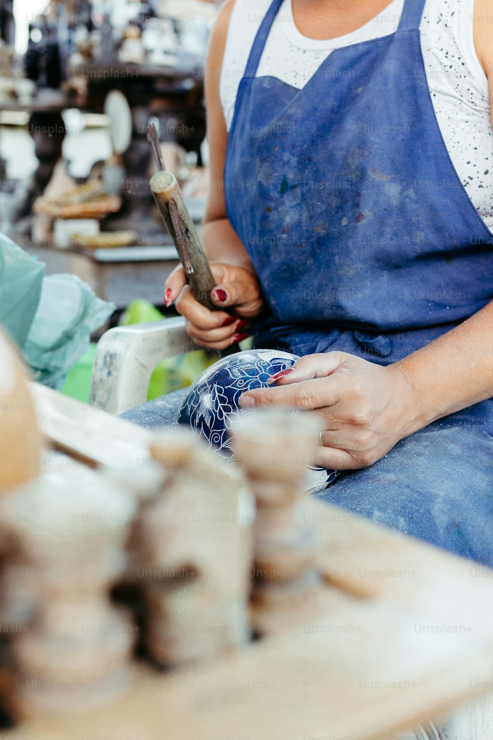 a woman in a blue apron working on a piece of wood