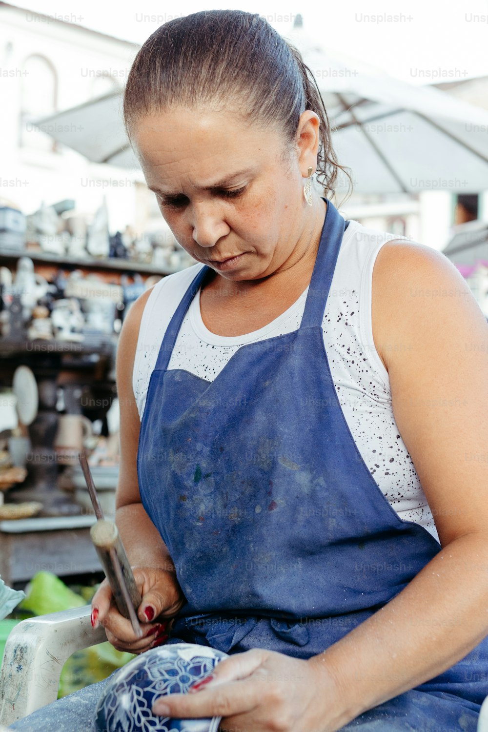 a woman in a blue apron working on a piece of pottery