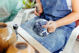 uma mulher sentada em uma cadeira com um vaso azul e branco