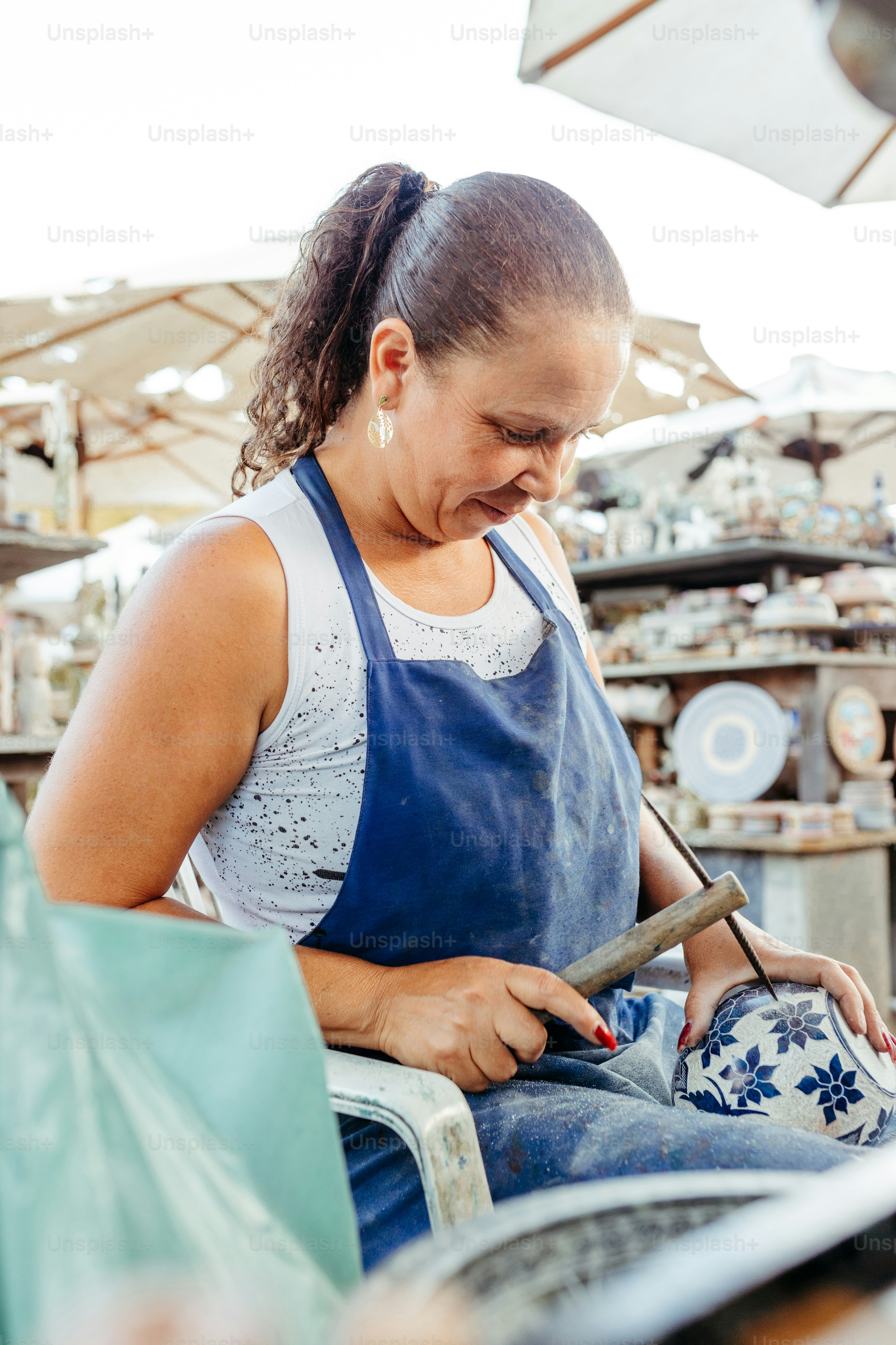 uma mulher sentada em uma cadeira trabalhando em um pedaço de cerâmica