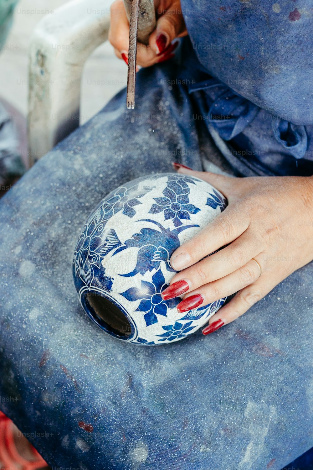 a woman is holding a blue and white vase