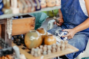 a woman is working on a vase in a shop