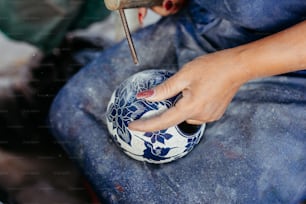 a person using a small tool to paint a vase