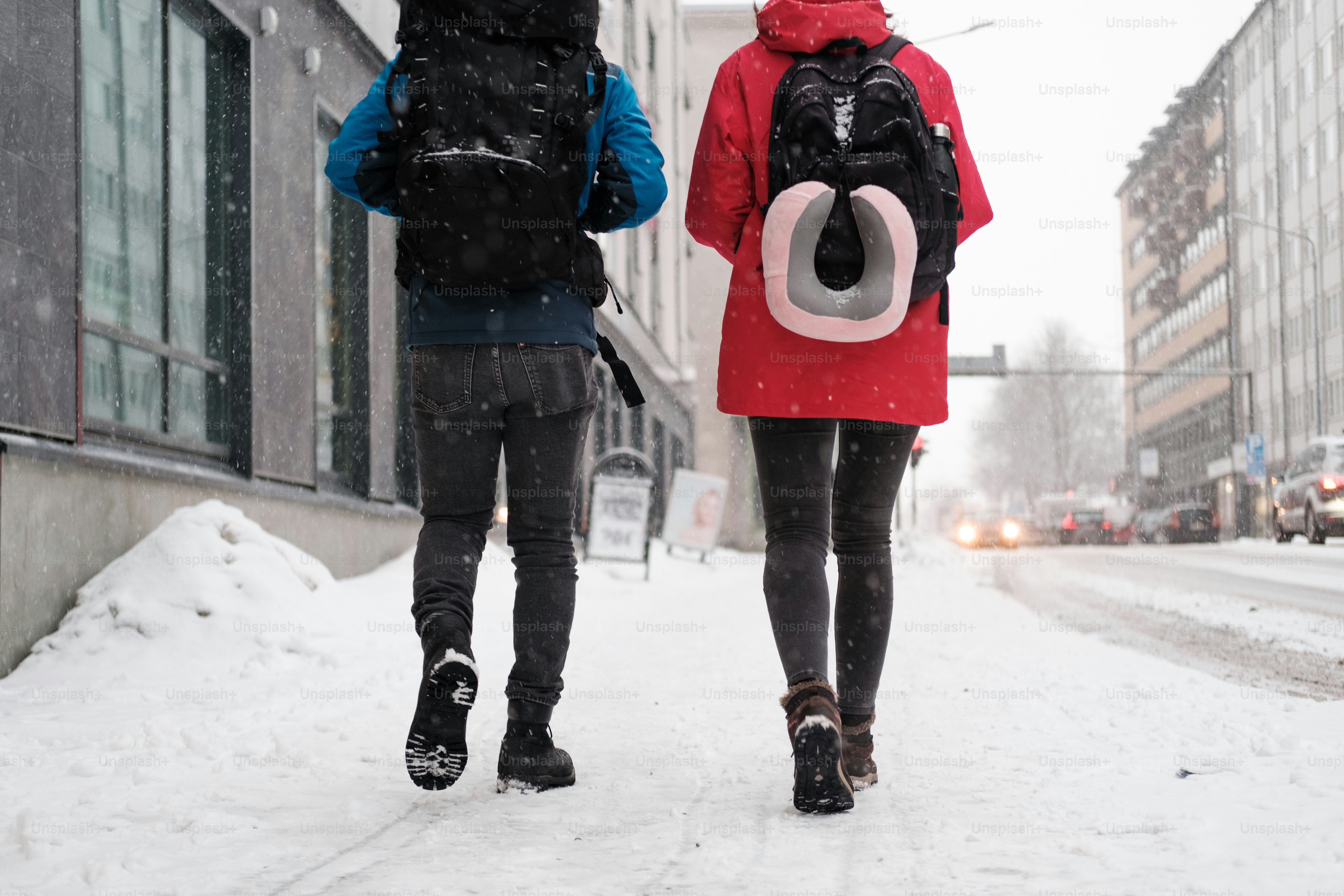 a couple of people walking down a snow covered street