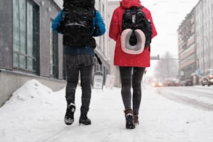 um casal de pessoas andando por uma rua coberta de neve