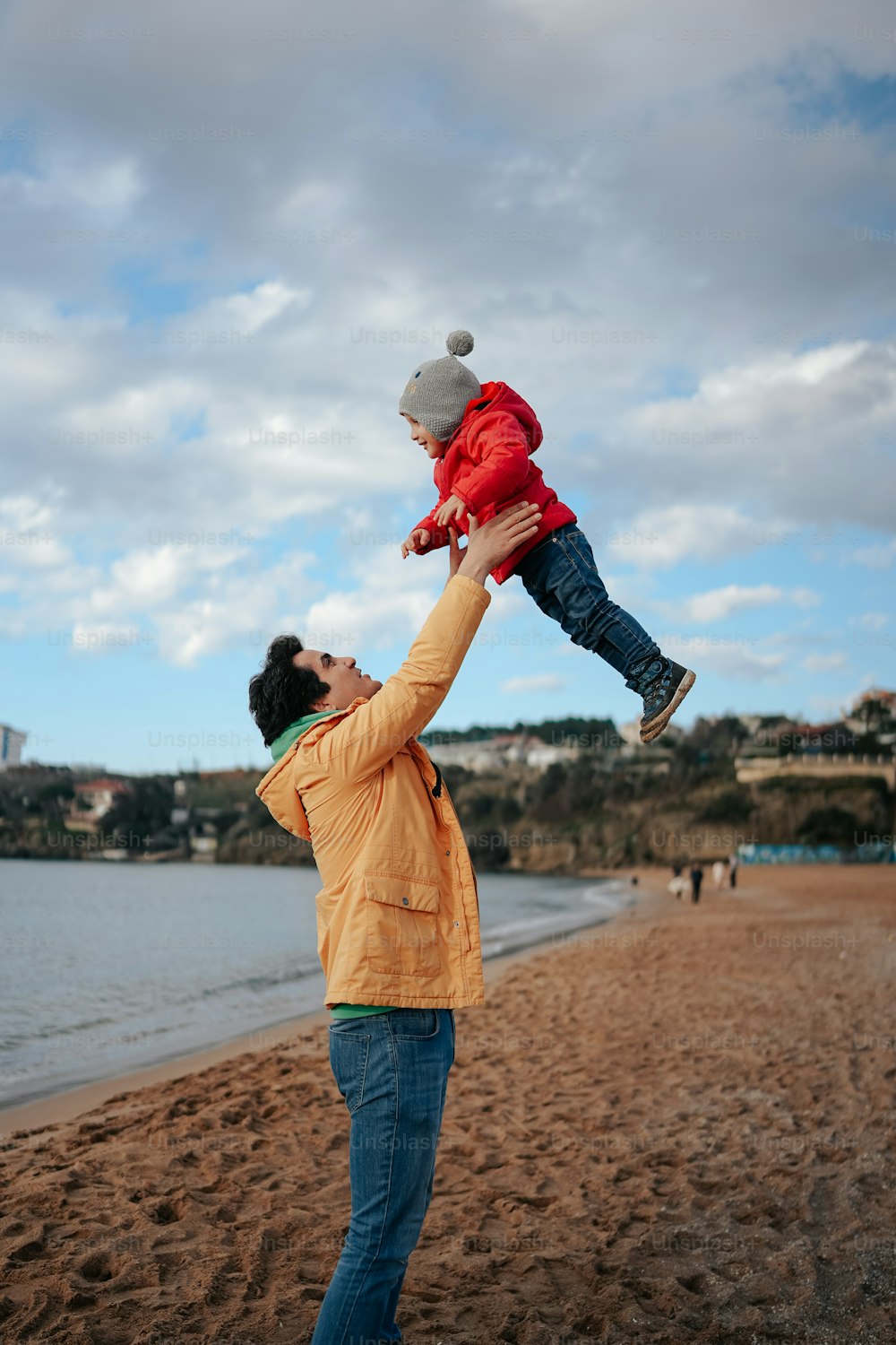 a man holding a child up in the air on a beach