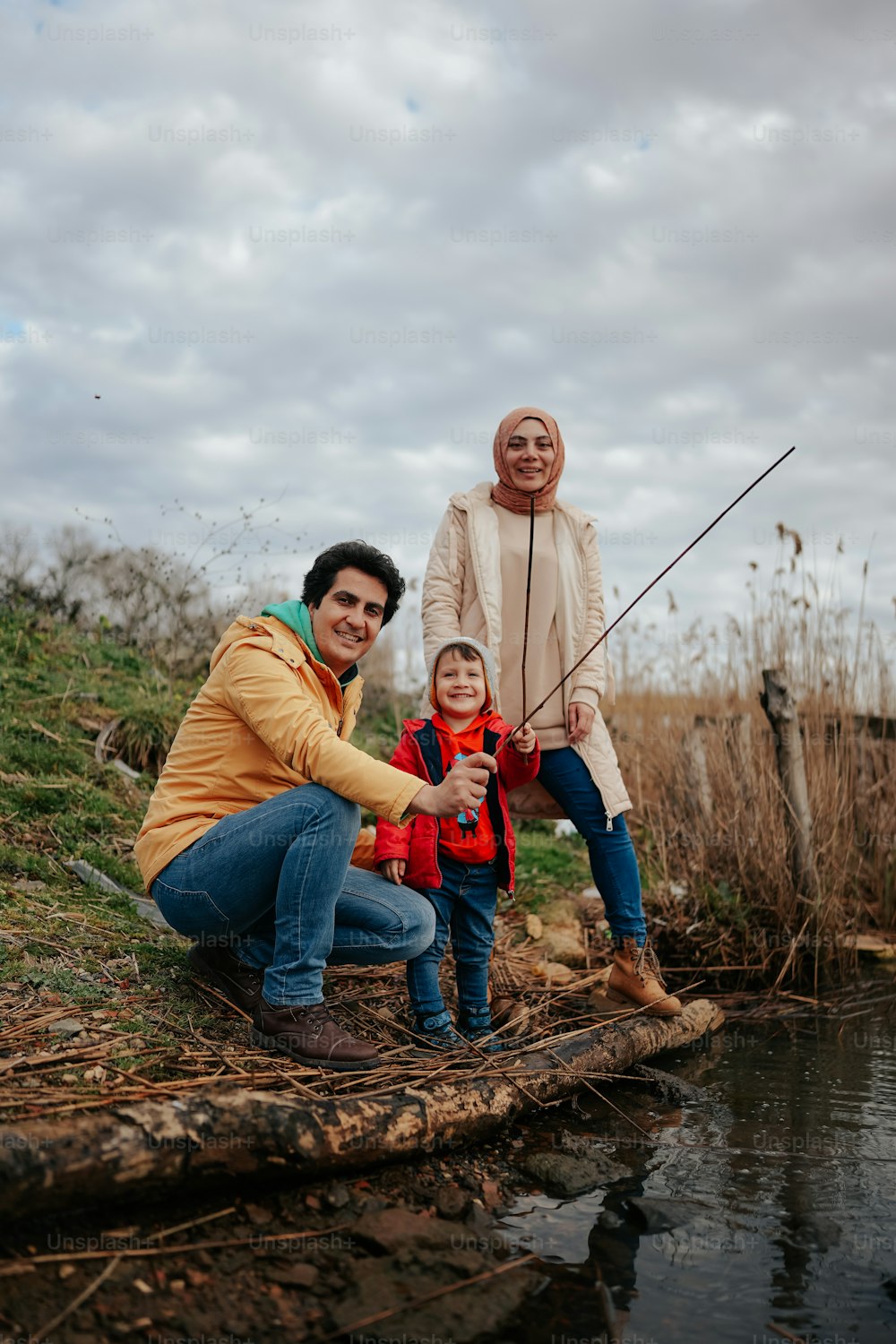 a man, woman and child fishing in a pond