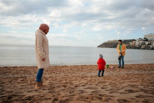 Una donna e due bambini in piedi su una spiaggia