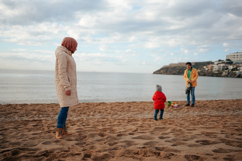 a woman and two children standing on a beach