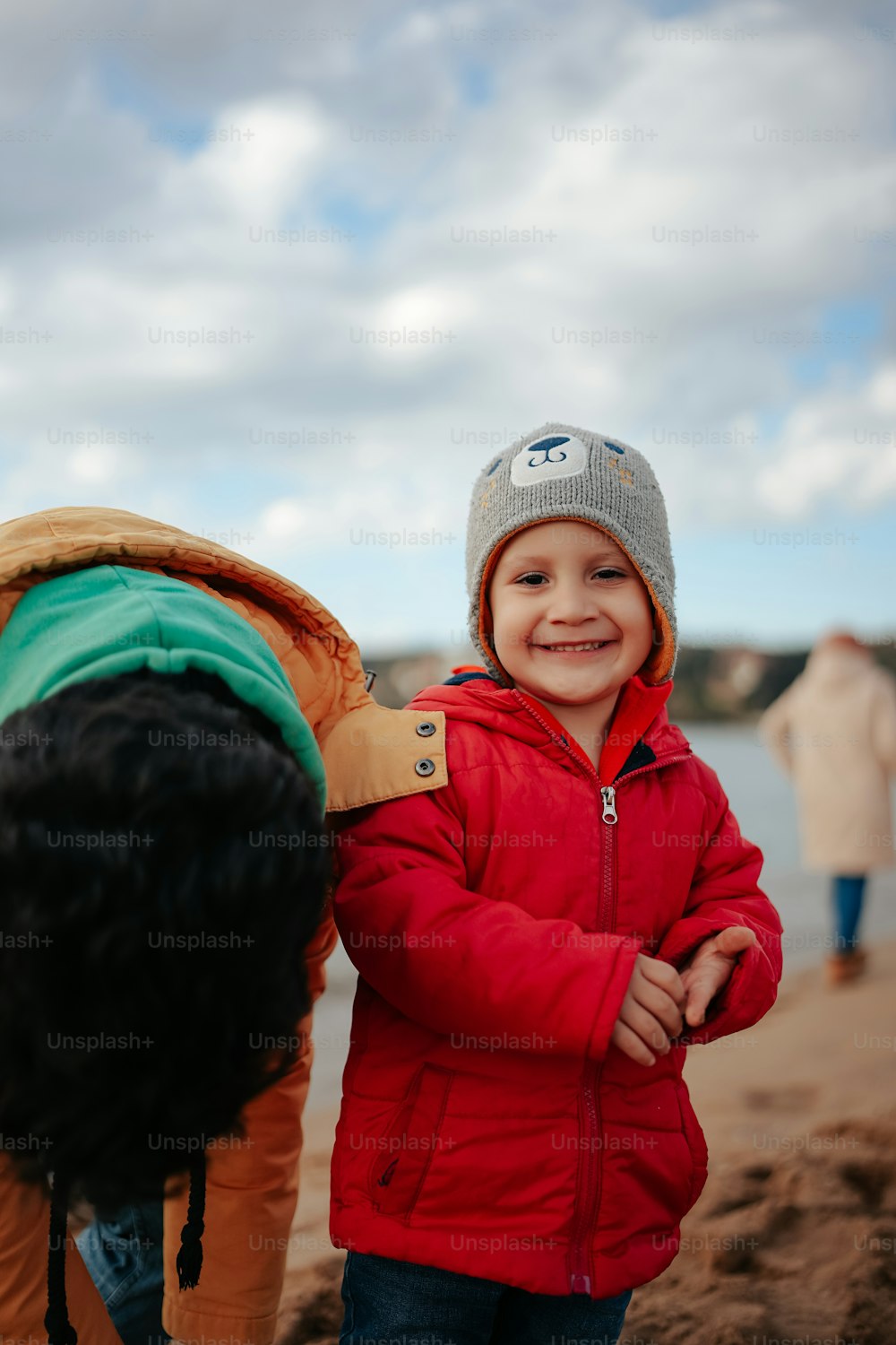 a little boy standing on a beach next to a horse