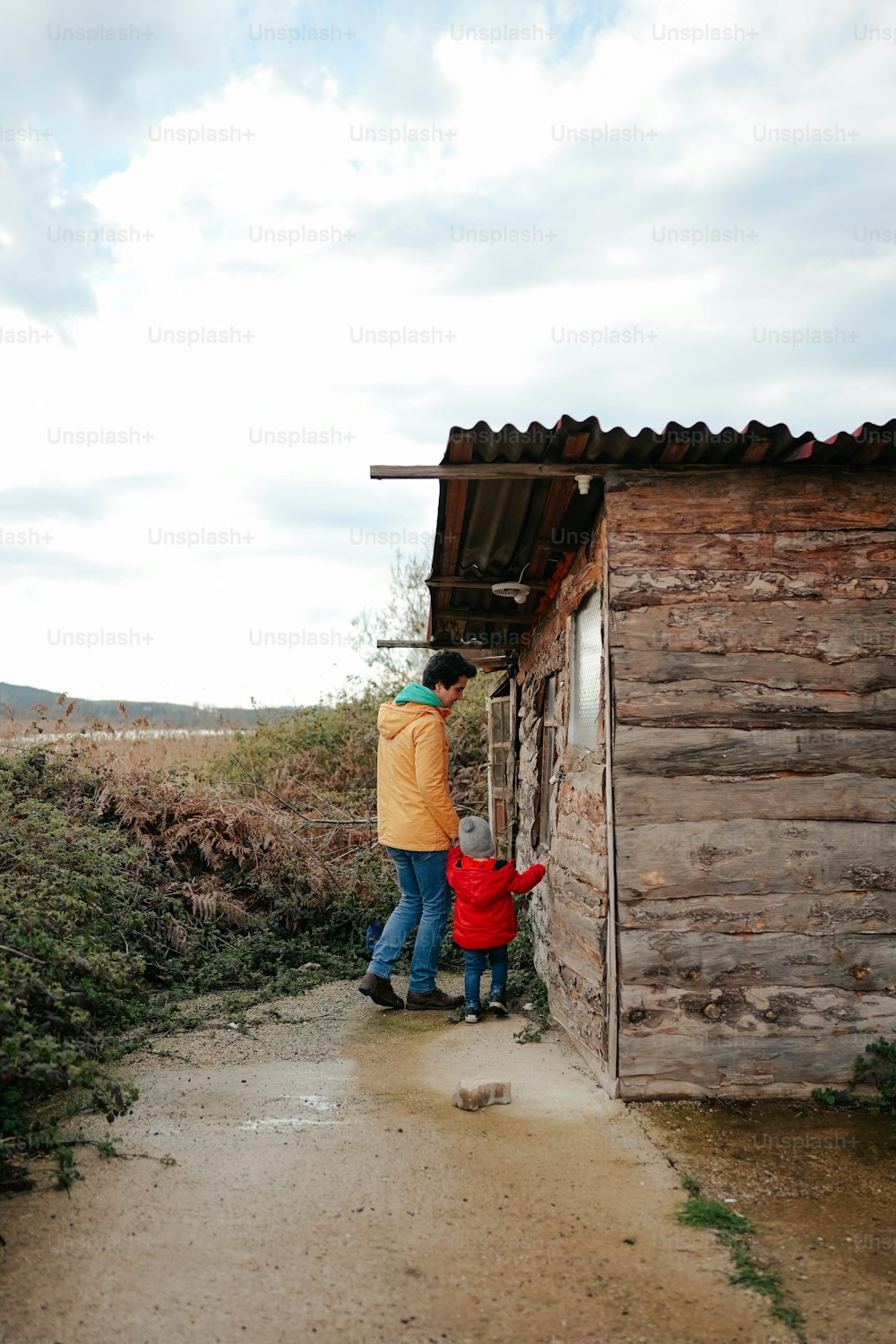 a man and a child standing outside of a cabin