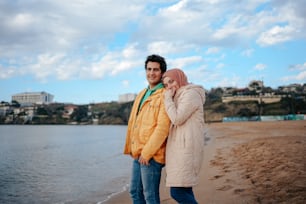 a man and a woman standing next to each other on a beach