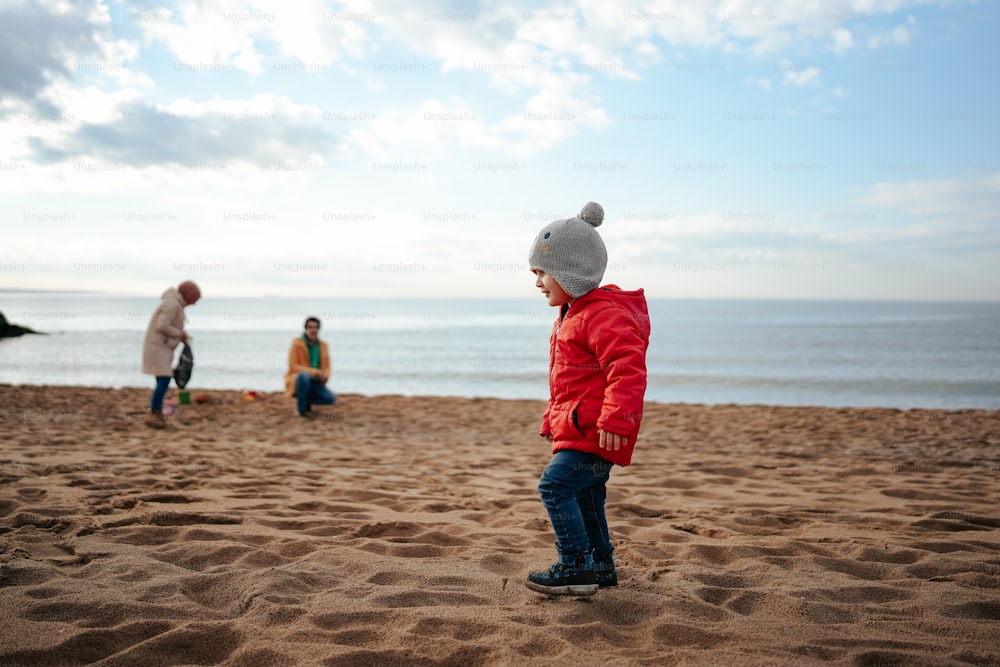 um menino de pé em cima de uma praia de areia