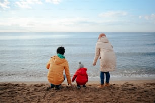 a woman and two children sitting on the beach
