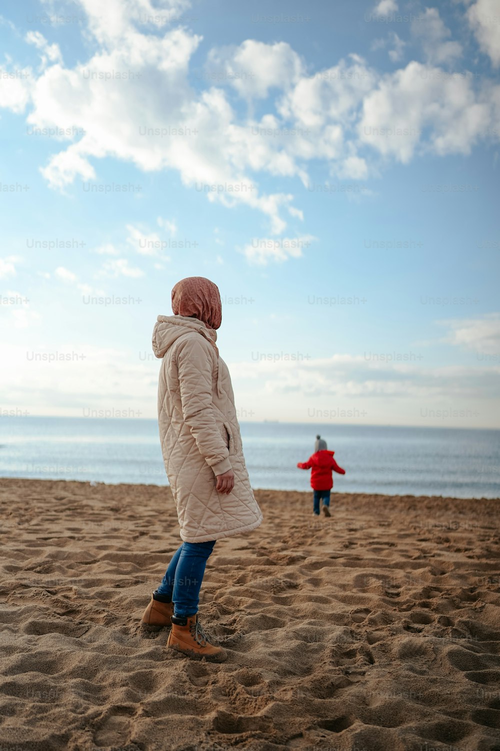 uma mulher em pé no topo de uma praia de areia