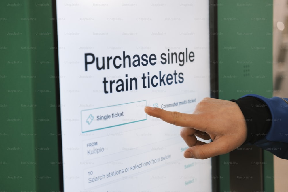 uma mão apontando para uma placa que diz comprar bilhetes de trem únicos