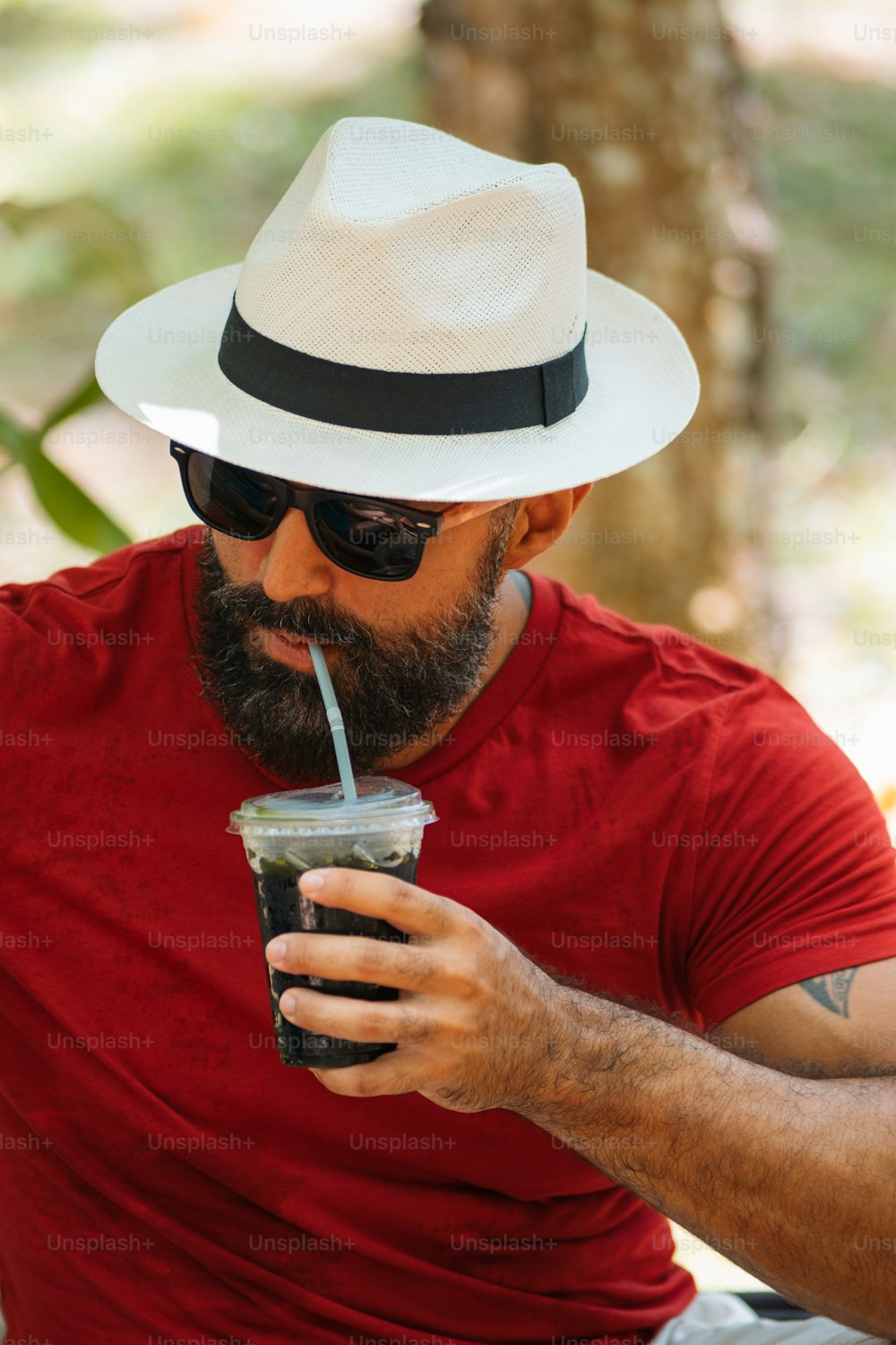 a man with a hat and sunglasses drinking a drink