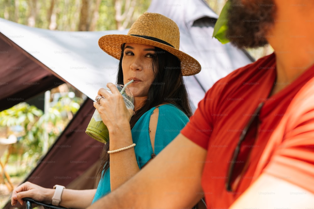 a woman in a straw hat drinking a glass of water