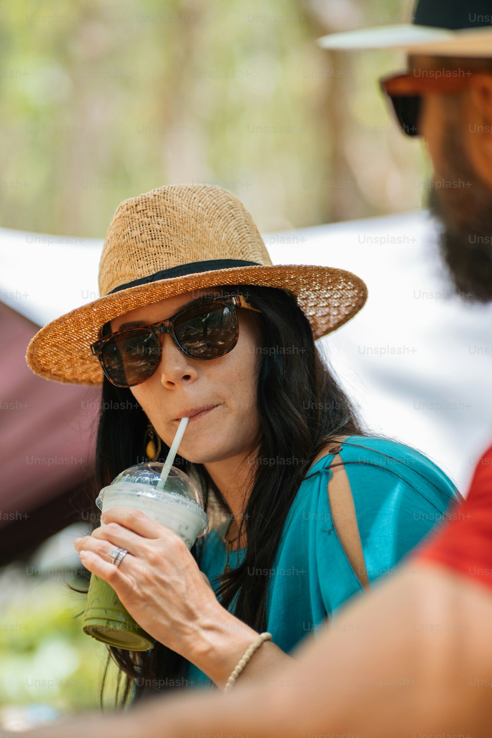 Eine Frau mit Strohhut, die ein Getränk trinkt