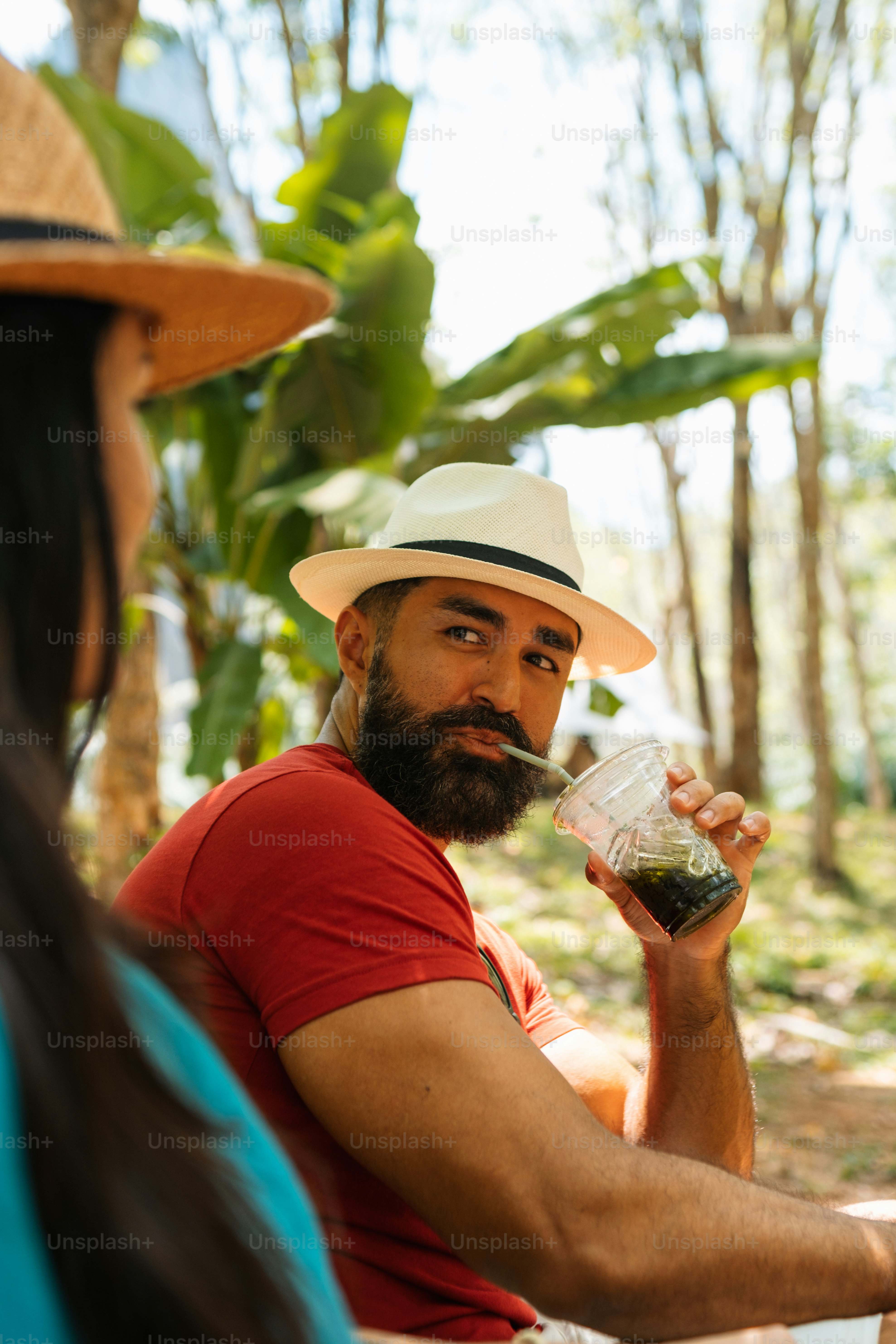Un hombre con barba y sombrero bebiendo de un vaso