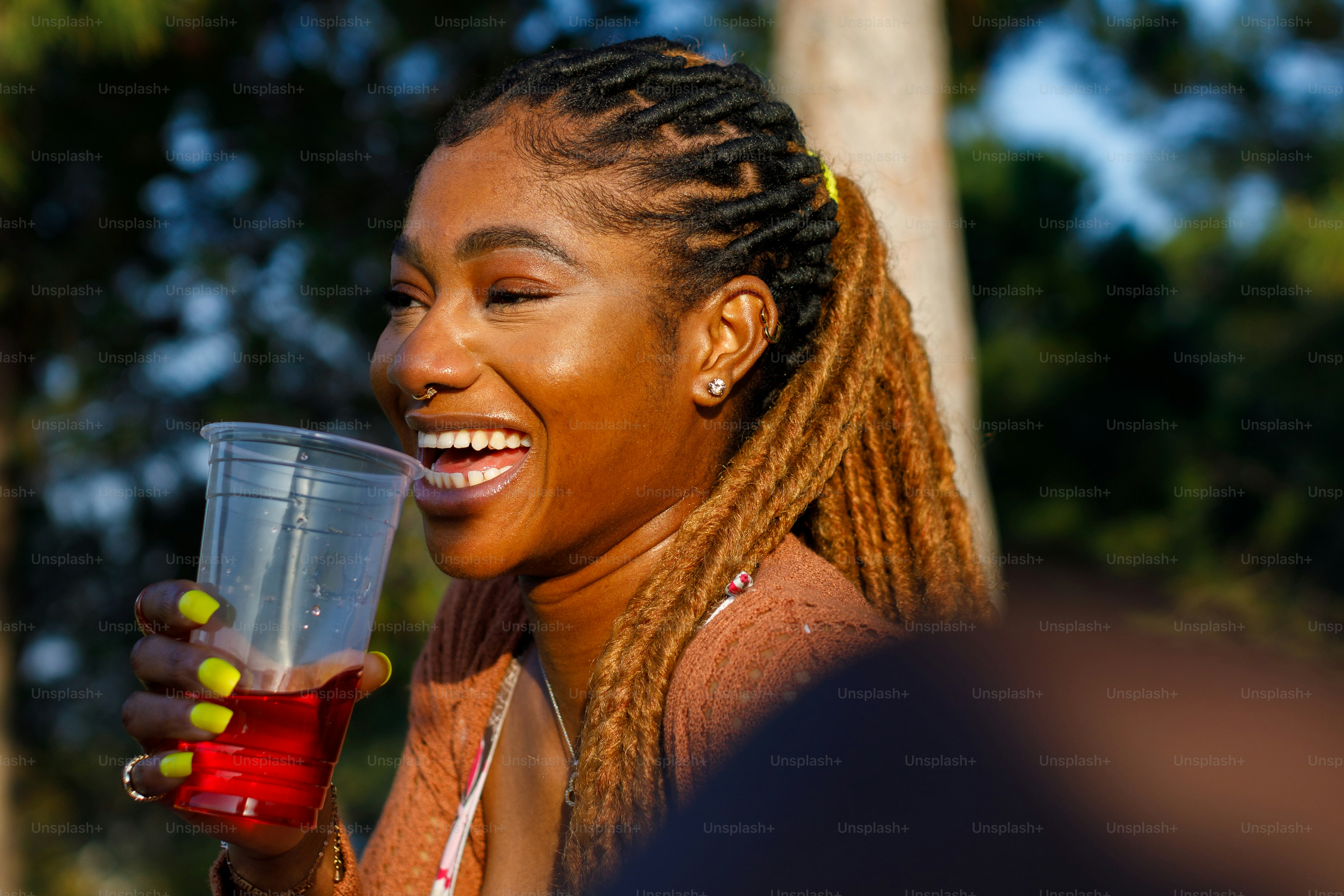 a woman with braids holding a drink and smiling