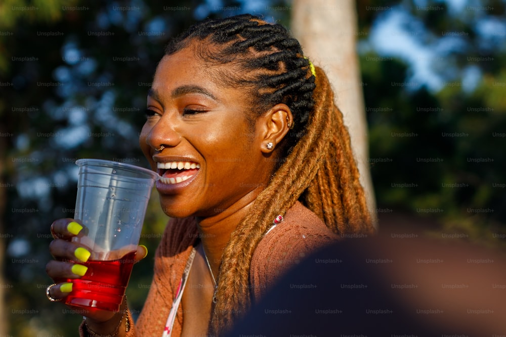 a woman with braids holding a drink and smiling