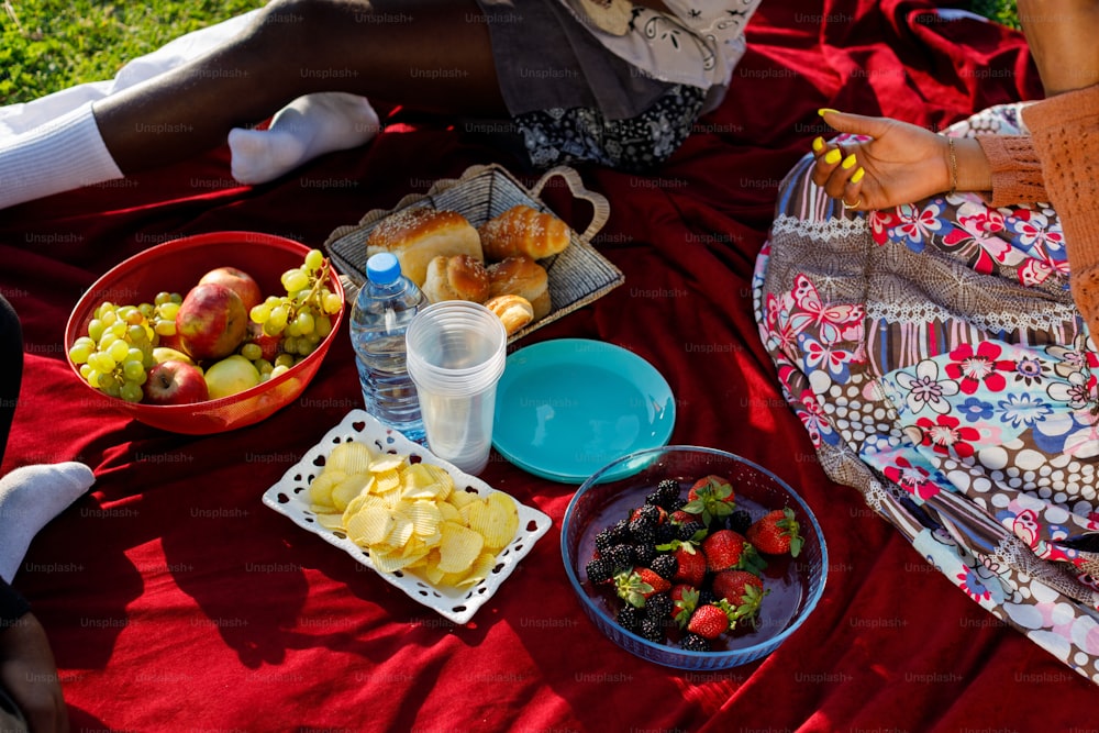 a woman sitting on a blanket with a bowl of fruit