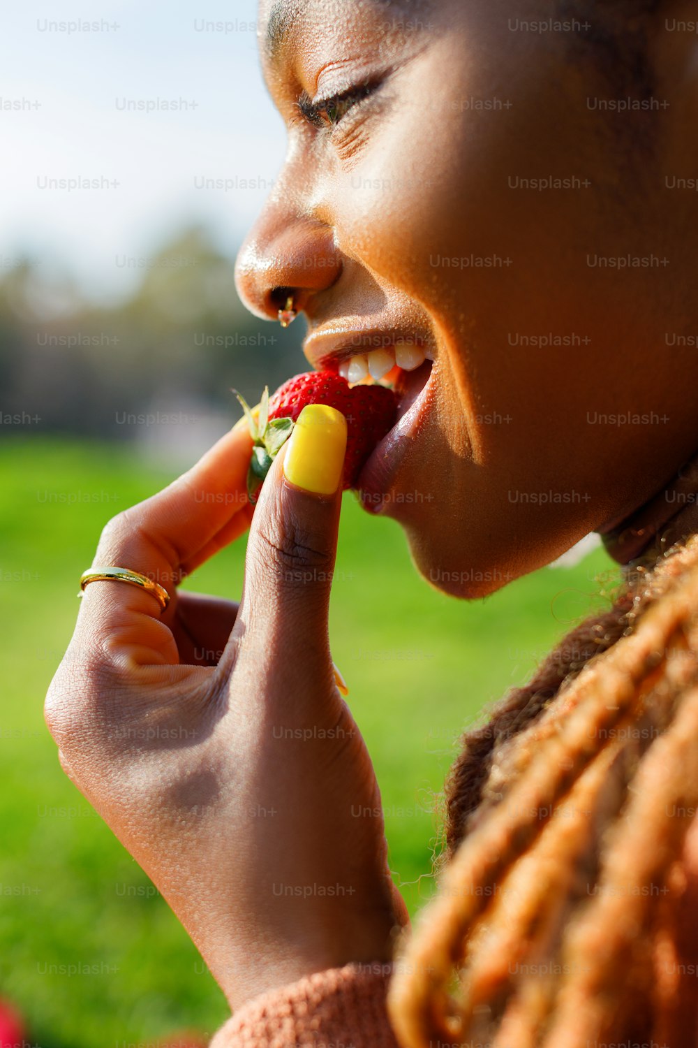 a woman eating a piece of fruit in a park