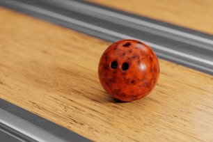 Una bola de boliche roja sentada encima de una mesa de madera
