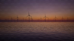 um grupo de moinhos de vento no oceano ao pôr do sol