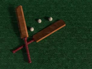 a wooden bat and three balls on a green surface