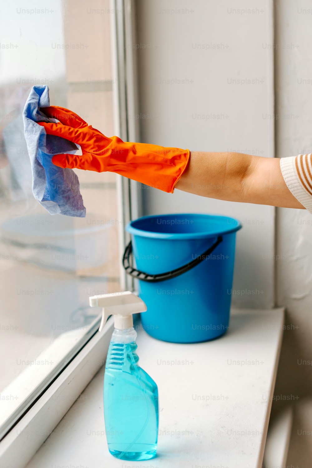 a person cleaning a window sill with a rag