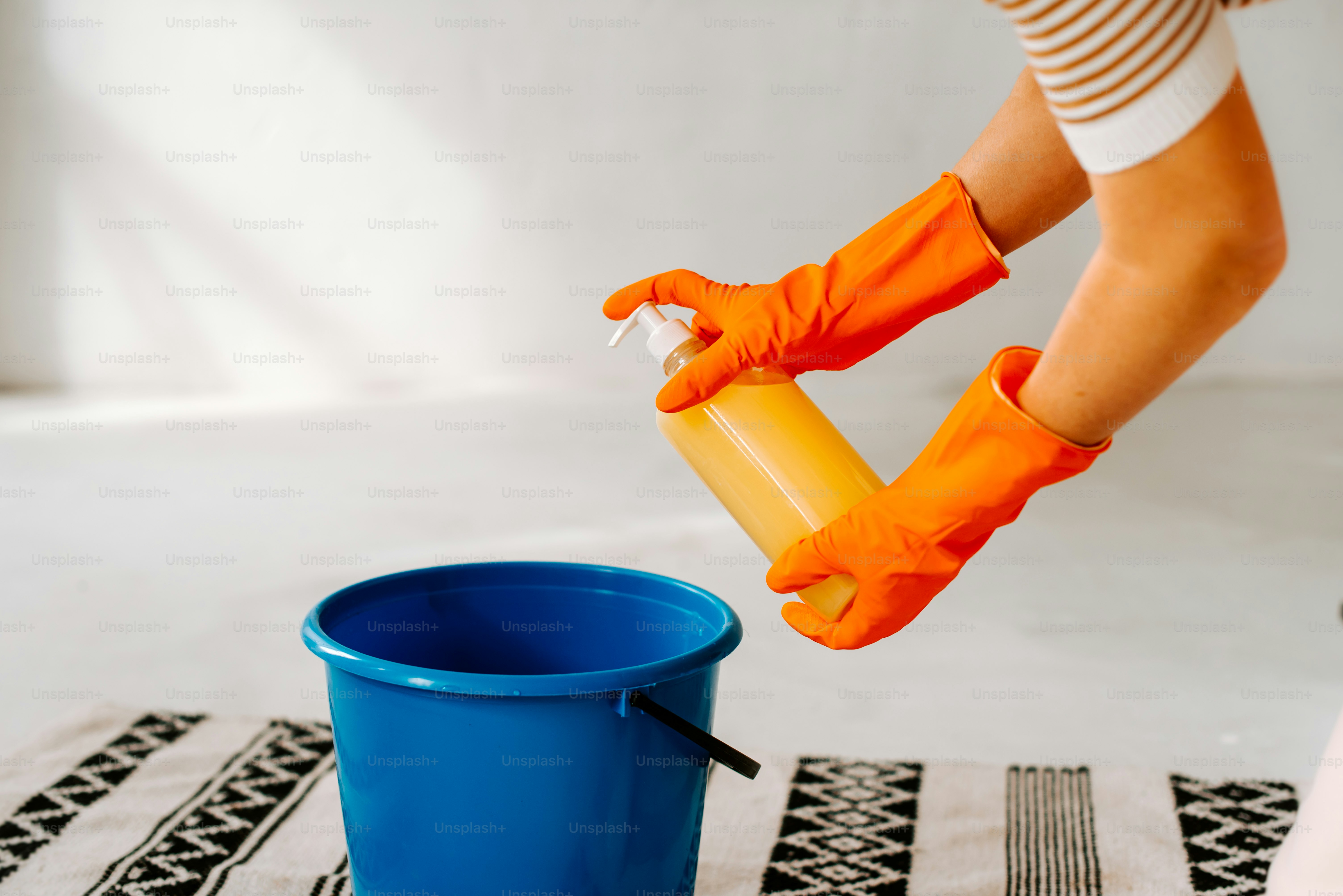 A woman in orange gloves is cleaning a blue bucket photo – Cleaning ...